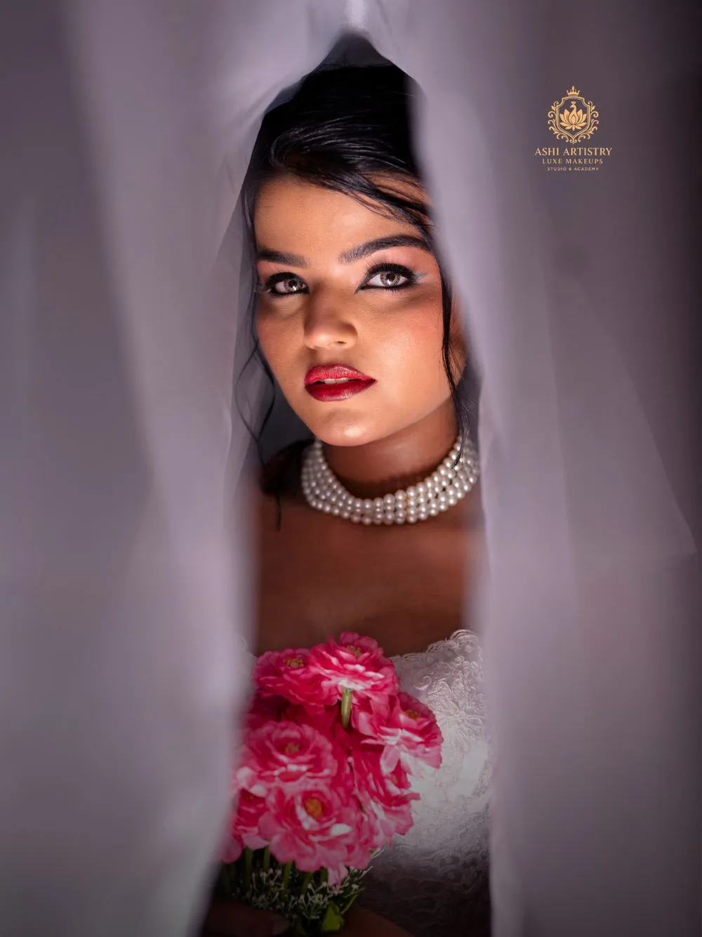 Bridal portrait peeking through a sheer veil, holding a pink bouquet