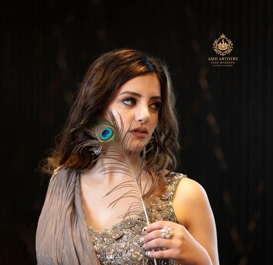 Studio portrait with a feather prop and gold drape